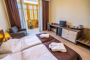 Una habitación de hotel con una cama, un escritorio, un televisor y una silla.