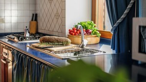Une cuisine équipée d’une cuisinière, d’un évier et d’un saladier rempli de légumes frais.