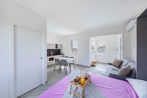A modern, well-lit room with a dining area, a sofa, and a bed. - San Carlo Borromeo by Wonderful Italy (Soiano del Lago)