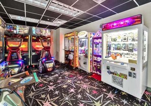 Ein Zimmer mit Spielautomaten, einem sternenmusterigen Boden und einer Verkaufsmaschine für unterschiedliche Artikel.
