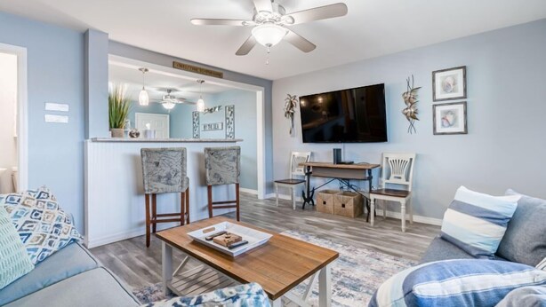 A living room with a sofa, a coffee table, a TV, and a ceiling fan.