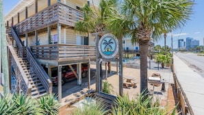 A wooden building with a balcony, palm trees, and a sign with a palm tree logo.