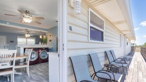 A covered porch with outdoor seating and a laundry area inside a house.