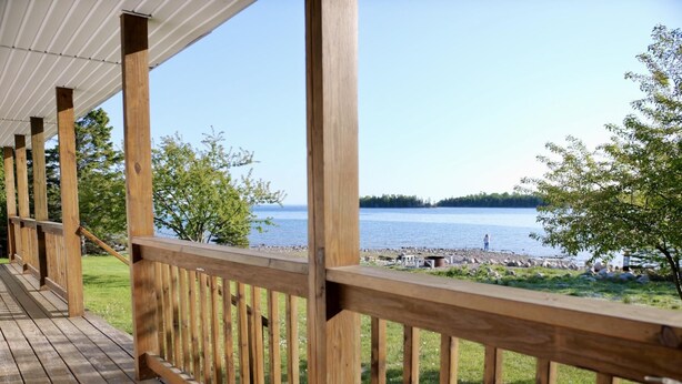 Ein Holzdeck mit Geländer, das auf einen See blickt.
