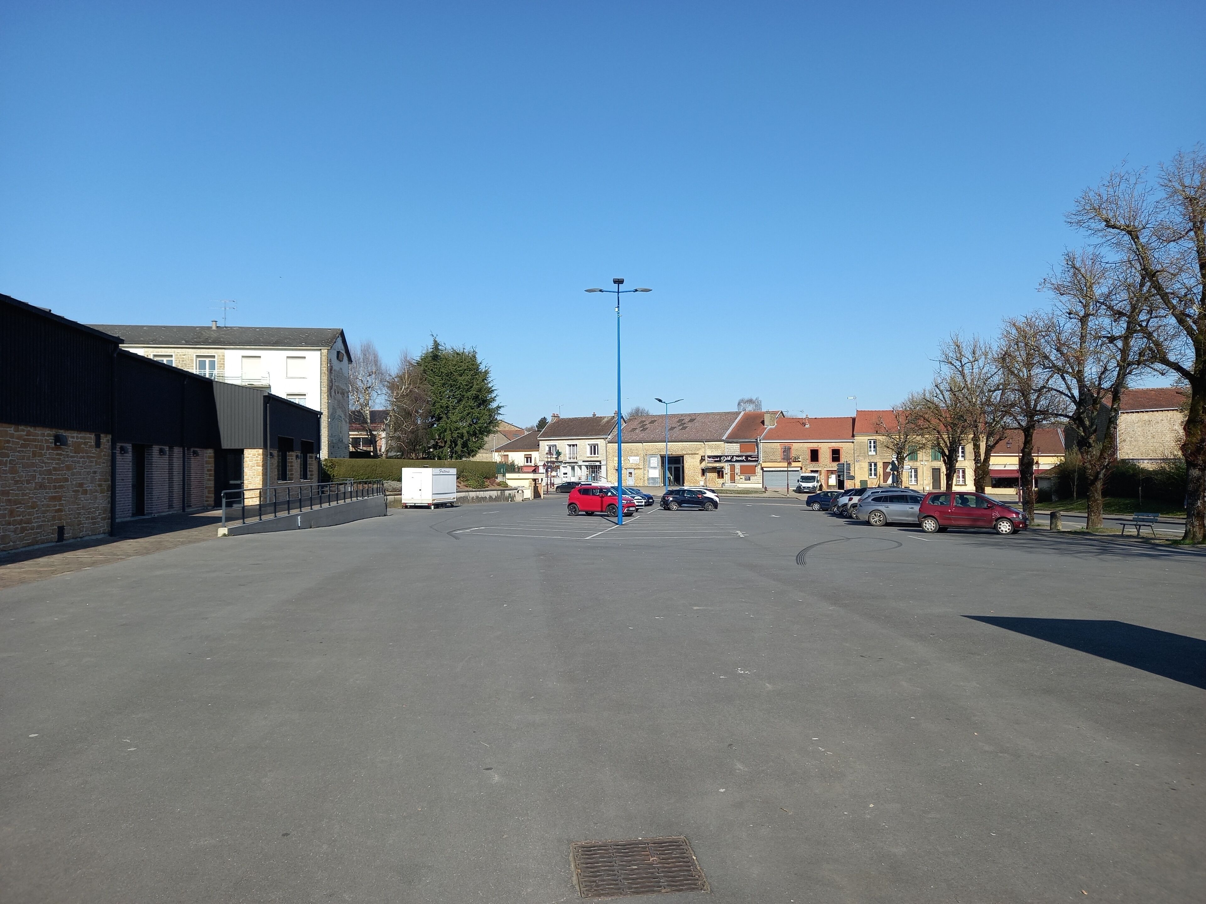Ein Parkplatz mit mehreren Autos, ein Gebäude mit einer Beschilderung und einem strahlend blauen Himmel.