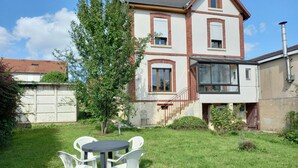 A two-story house with a brick facade, a small front yard with a round table and four chairs, and a tree. - La Locomotive by la Bb12087 (Nouvion-sur-Meuse)