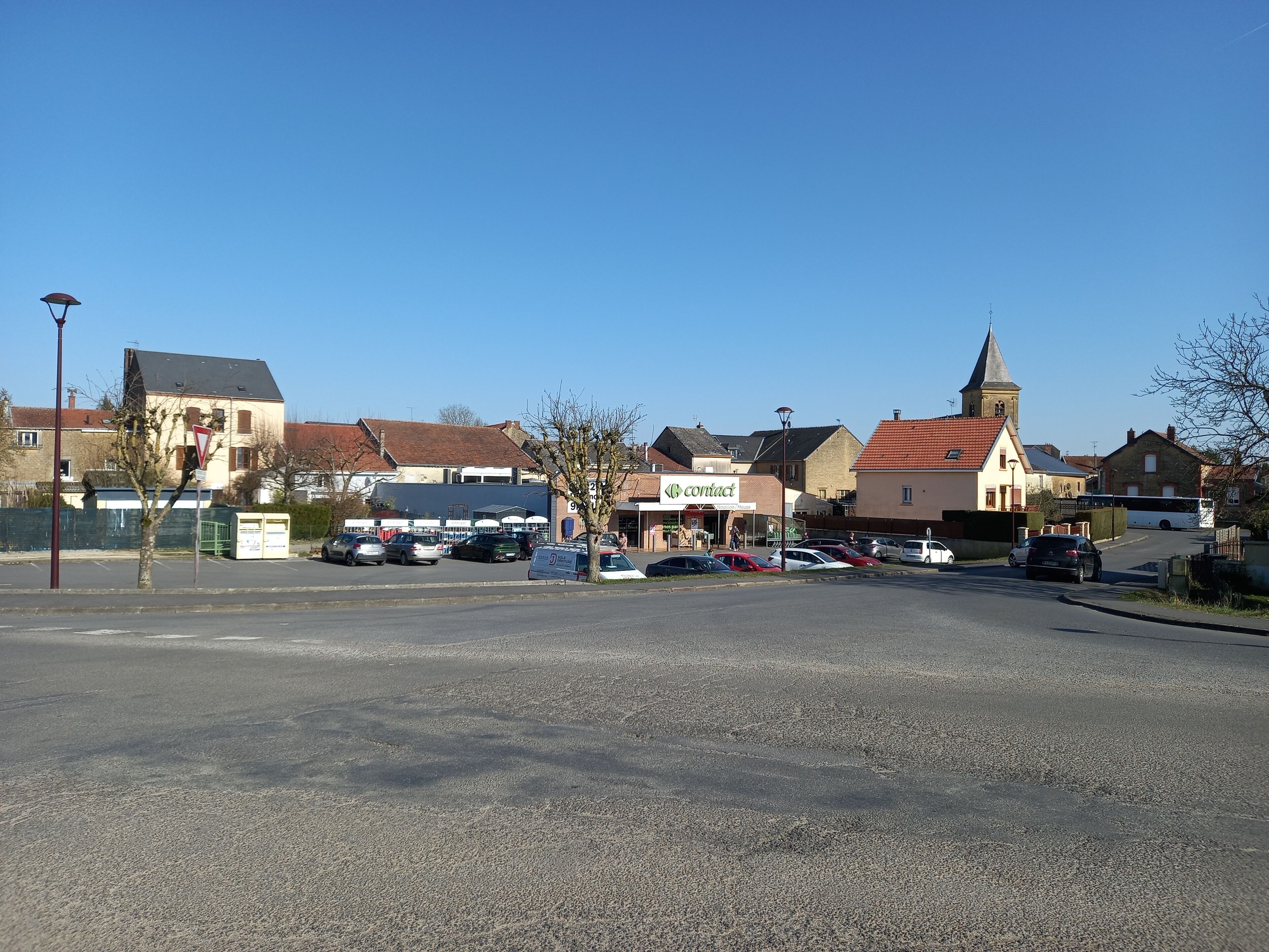 A parking lot with several cars, a church with a steeple, and a building with a 'contact' sign.
