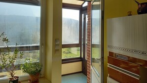 A room with a large window, a potted plant, and a wooden cabinet. - La Locomotive by la Bb12087 (Nouvion-sur-Meuse)