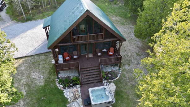 Eine Hütte mit überdachter Terrasse, Sitzgelegenheiten im Freien und einem Whirlpool.