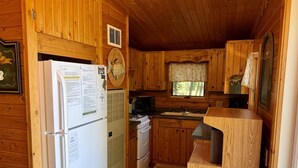 Una cocina tipo cabaña con armarios de madera, un refrigerador, una estufa y un lavamanos.
