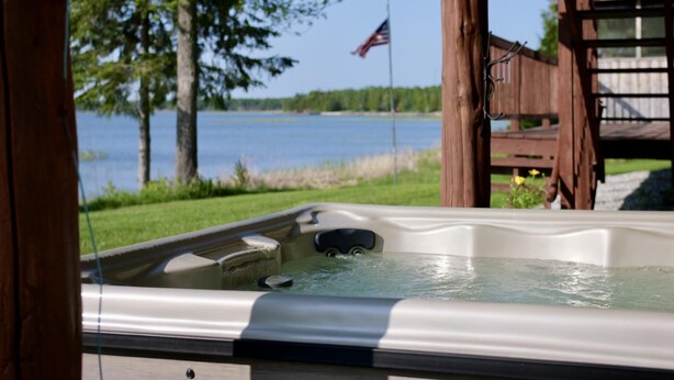 Un jacuzzi con vista a un lago y una bandera estadounidense al fondo.