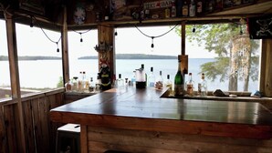 Un bar rústico con paredes de madera y un amplio ventanal con vistas a un lago.