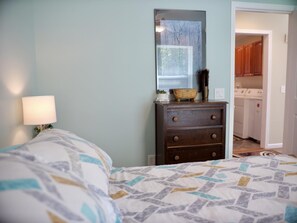 A bedroom with a bed, dresser, and a mirror.