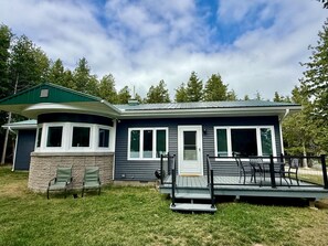 A two-story house with a covered porch and a small deck. - Dockside on Drummond Island (Drummond Island)