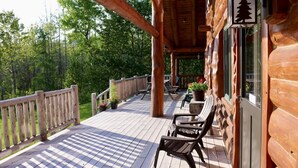 A wooden deck with a railing, potted plants, and outdoor furniture. - Paw Point Lodge on Drummond Island (Drummond Island)
