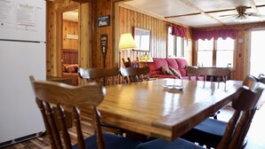A wooden dining area with a table and chairs, a red sofa, and a lamp.