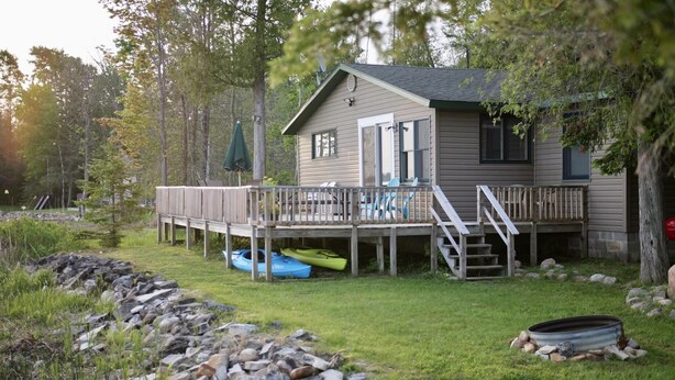 A cabin with a deck, outdoor seating, and kayaks.