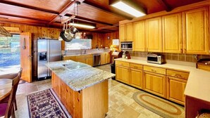Una cocina con armarios de madera, encimera de granito, electrodomésticos de acero inoxidable y vistas al exterior.