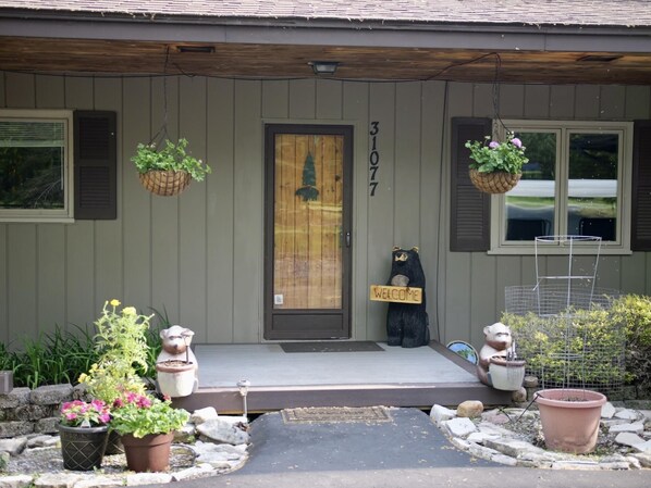 A house with a wooden door, a welcome sign, and two potted plants on the porch. - Lakeside Ranch on Drummond Island (Drummond Island)