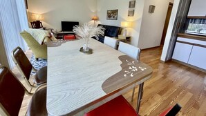Un coin repas avec une table en bois, des chaises et un vase contenant des plantes séchées.