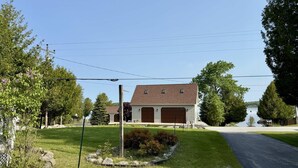 Une maison à deux étages avec un garage, entourée d’une pelouse bien entretenue et d’arbres.