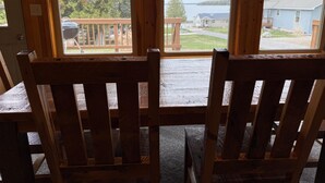 Une terrasse en bois avec deux chaises, donnant sur une maison et un plan d’eau.