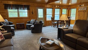 Un intérieur de chalet chaleureux comprenant un salon, un coin repas et une enseigne indiquant un magasin de vente d’appâts.