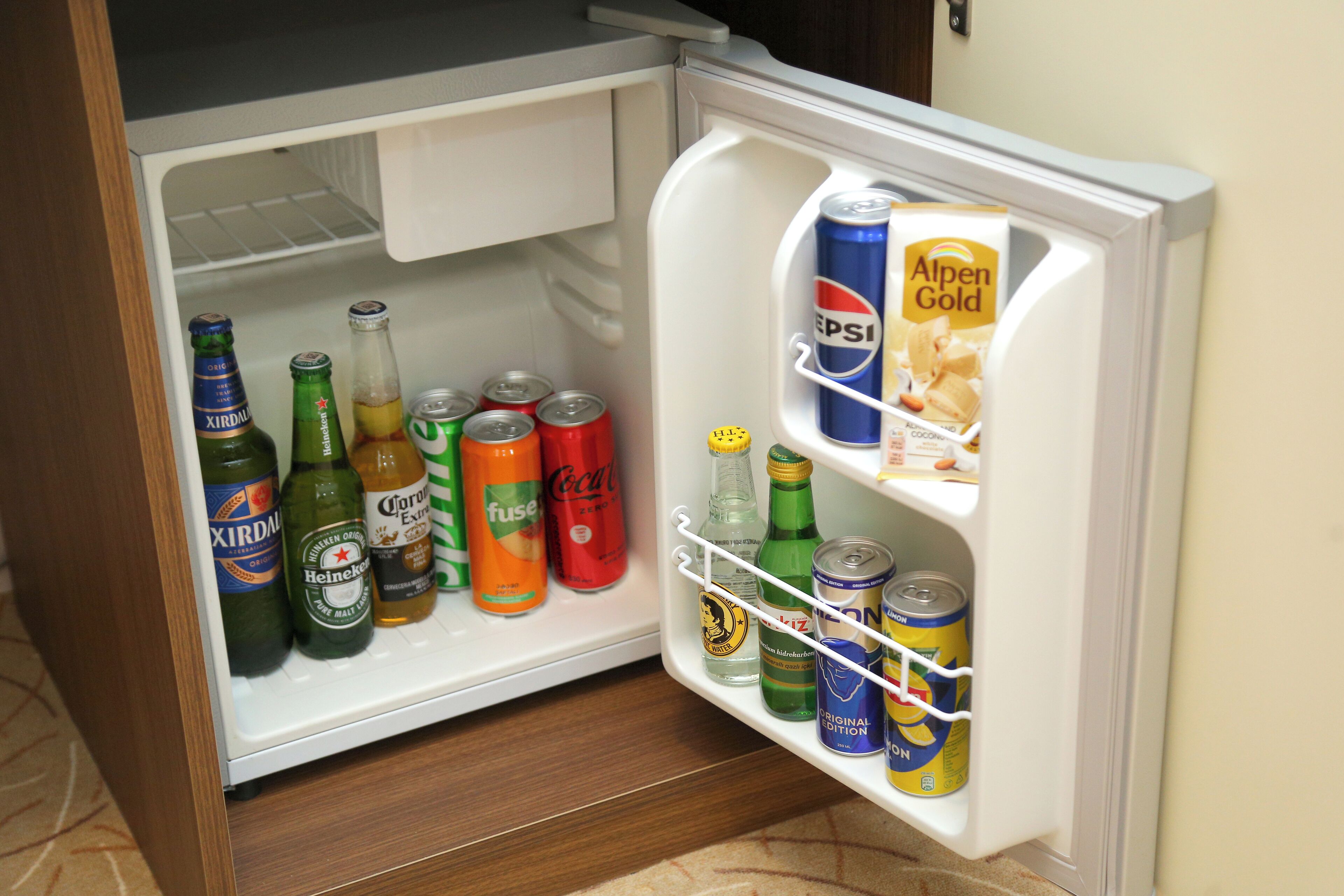 A refrigerator with various beverages including beer, soda, and energy drinks.