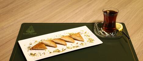 A plate of triangular pastries with a glass of tea on a wooden table.