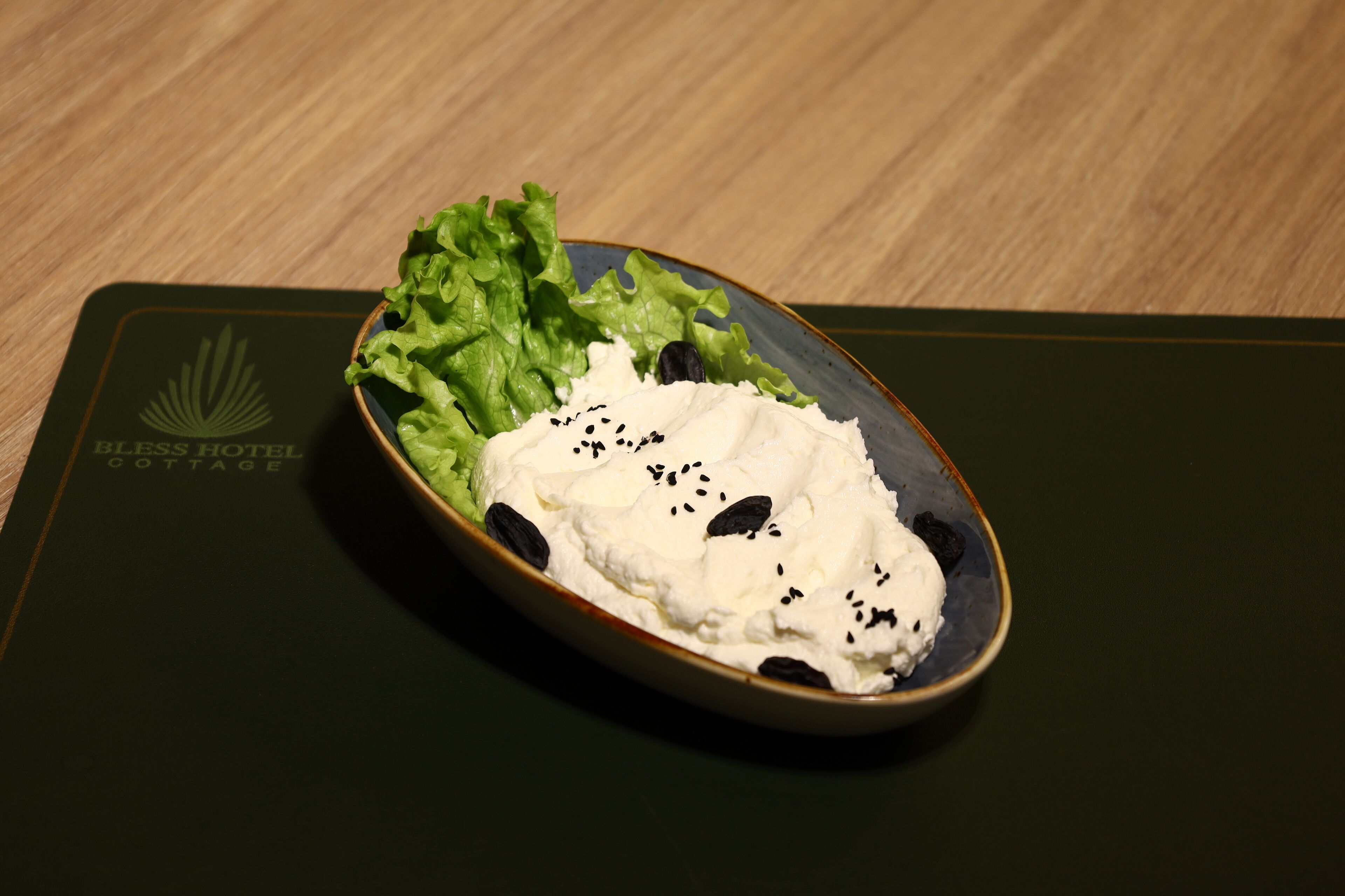 A bowl of food on a placemat with the text "BLOSS HOTEL COTTAGE" visible.
