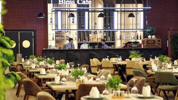 Un restaurante con mesas dispuestas para comer, una zona de bar y un panel de menú visible.