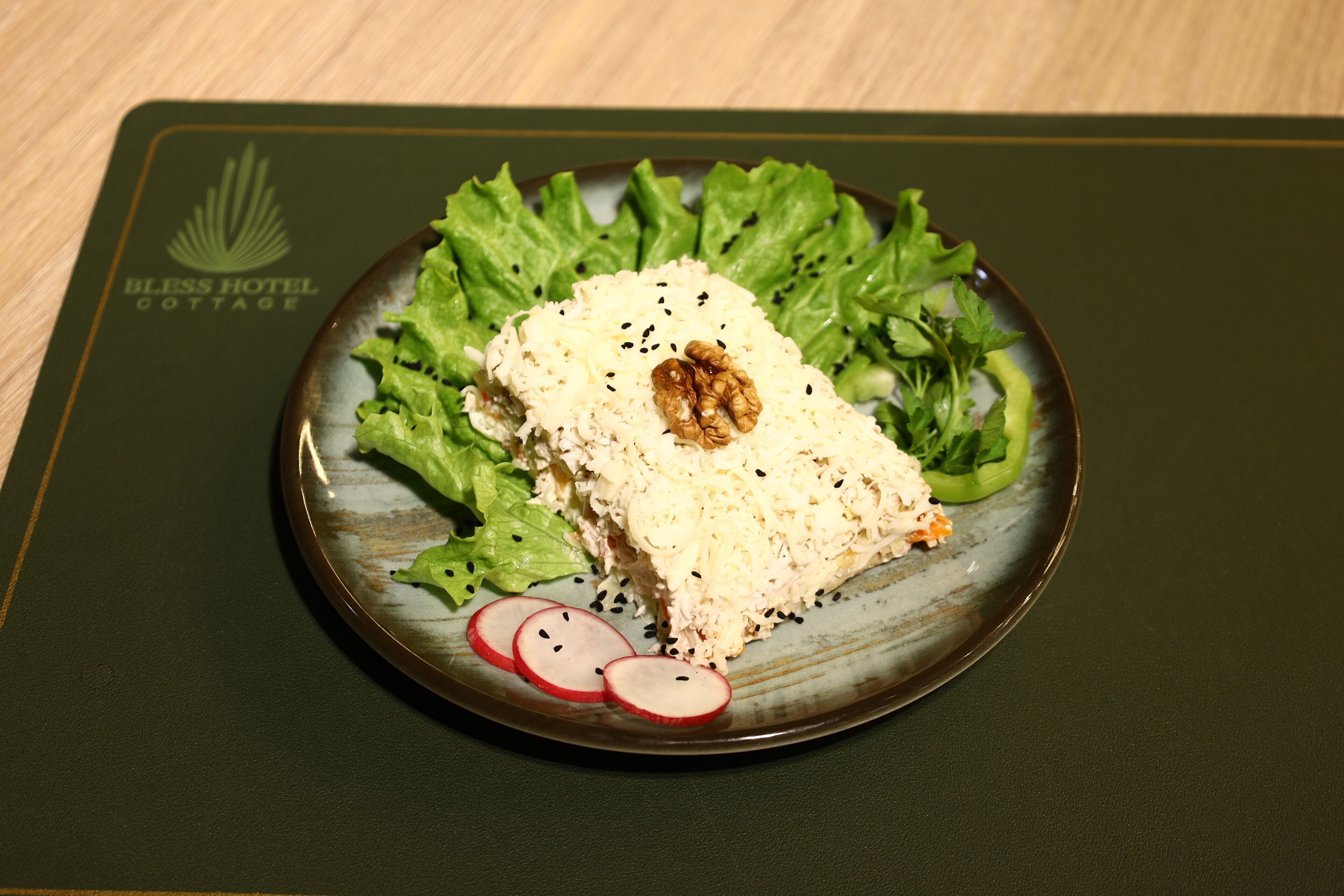 A plate of food with a walnut on top, served on a green placemat with a logo.