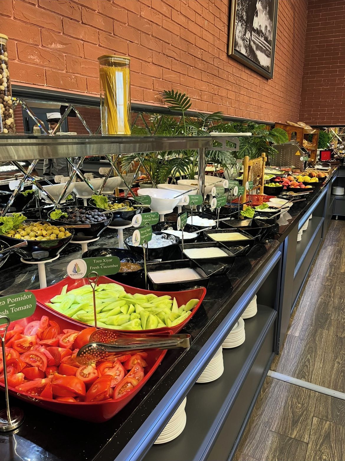 Un bufé con diversos alimentos, entre ellos tomates frescos, pepinos y una variedad de frutas y verduras.
