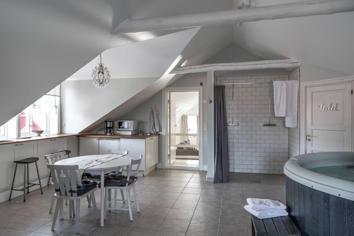 A modern kitchen with a dining area, a hot tub, and a view of the adjacent room.