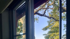 Una ventana con vista a un lago, una terraza de madera y una lámpara en el alféizar.