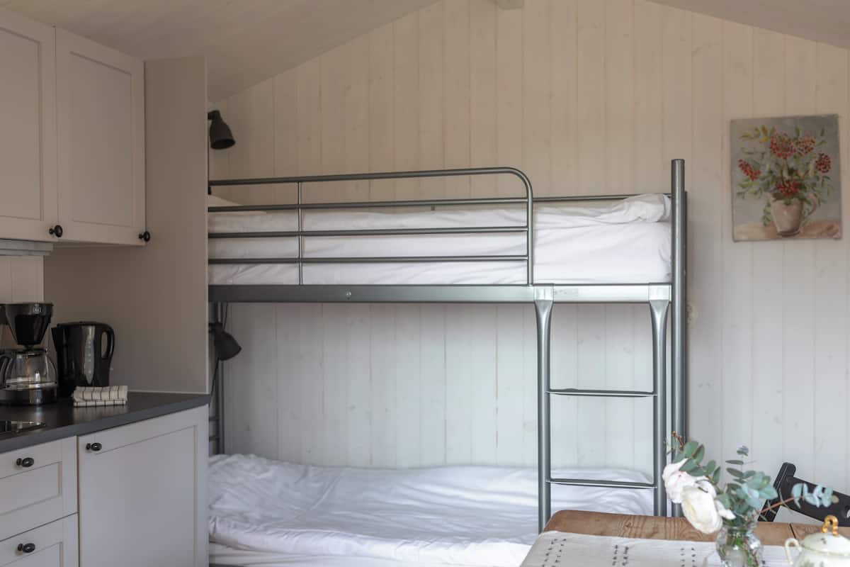 A bunk bed room with a desk, a coffee maker, and a painting on the wall.