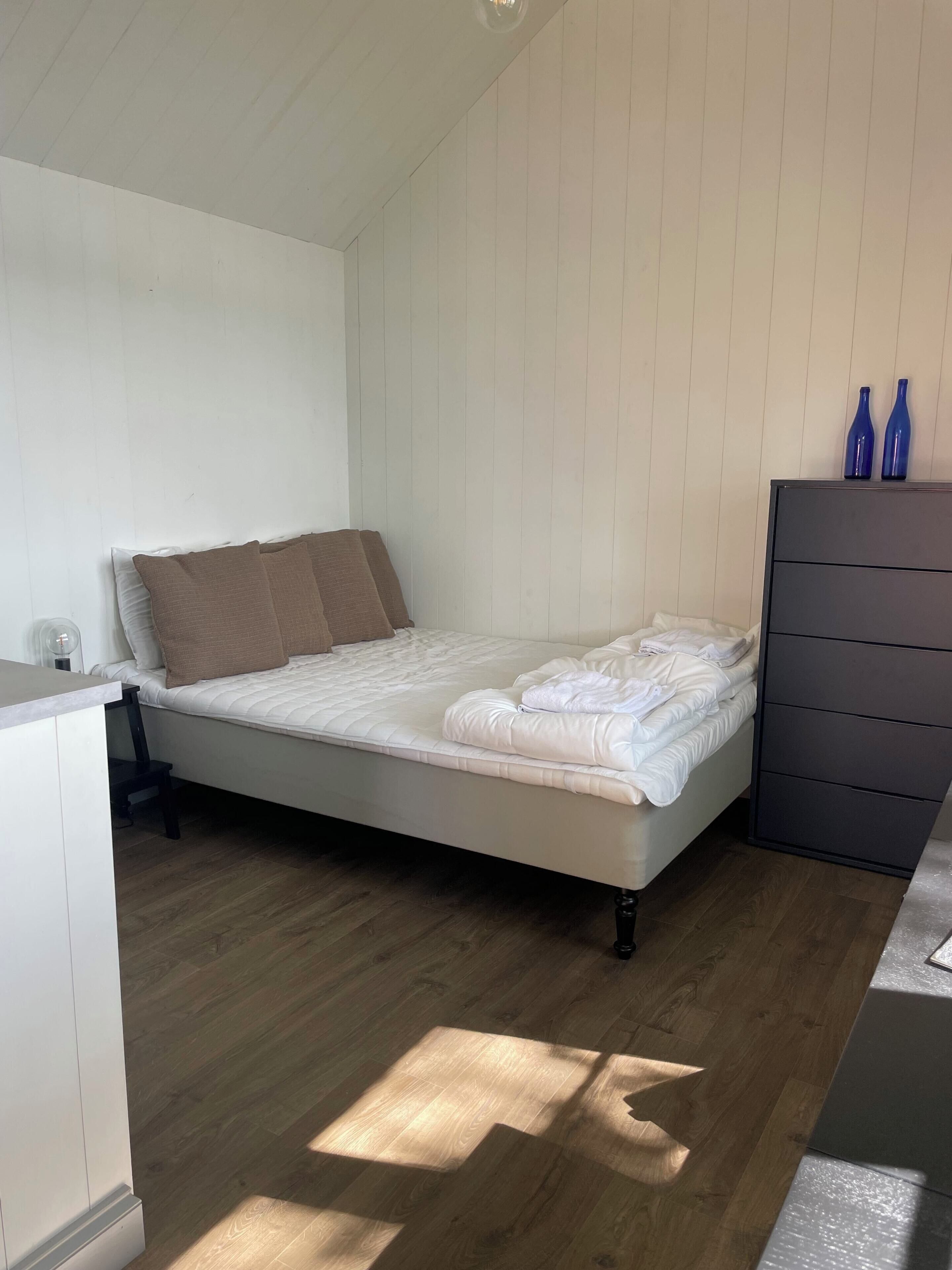 A bedroom with a bed, a dresser, and two blue bottles on top.