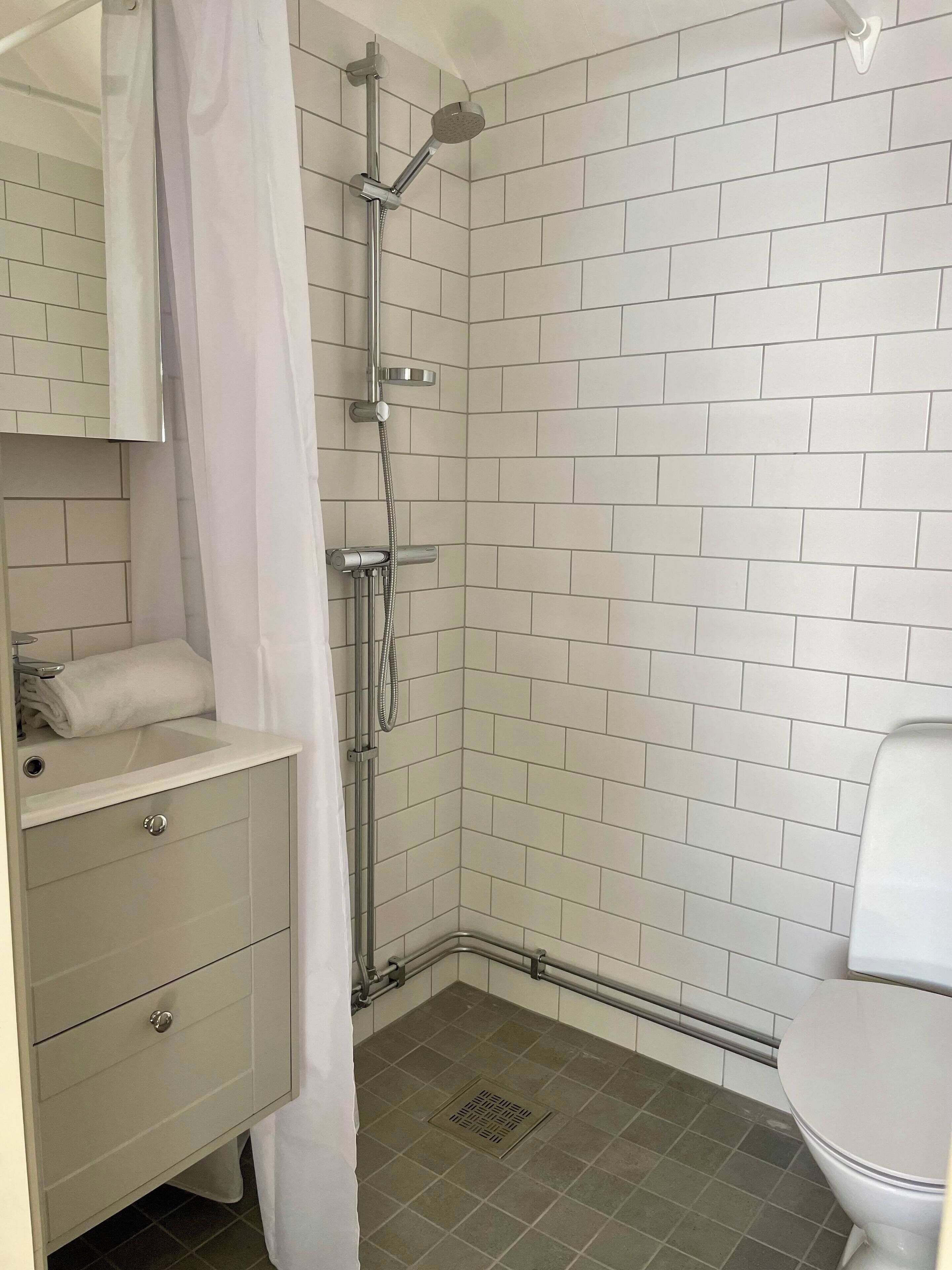 Ein Badezimmer mit Dusche, Toilette, Waschbecken und Spiegel.