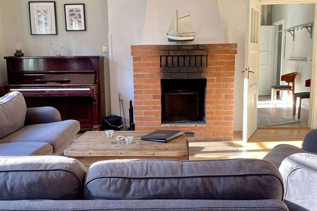 A living room with a fireplace, a piano, and a sofa.