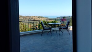 A balcony with a table and chairs, offering a view of a hilly landscape and the sea. - Granatelli Holiday Home (Altavilla Milicia)