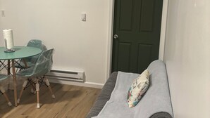 Et lille, pænt møbleret værelse med seng, et bord med stole og en dør.