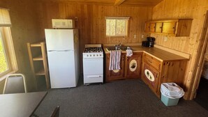 Eine kleine Küche mit Kühlschrank, Herd, Spüle und Holzschränken.