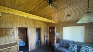 Ein Holzhütten-Interieur mit einer Couch, einem Holzschrank und einem Deckenventilator.