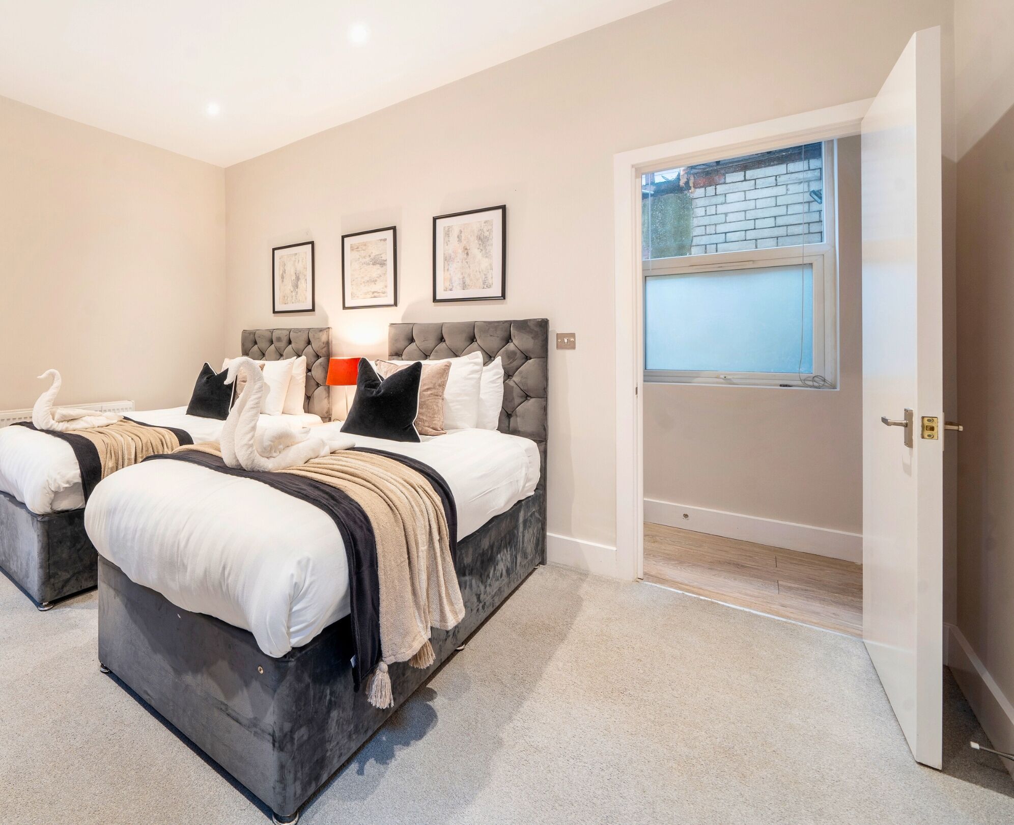 A bedroom with two beds, a large window, and a door leading outside.