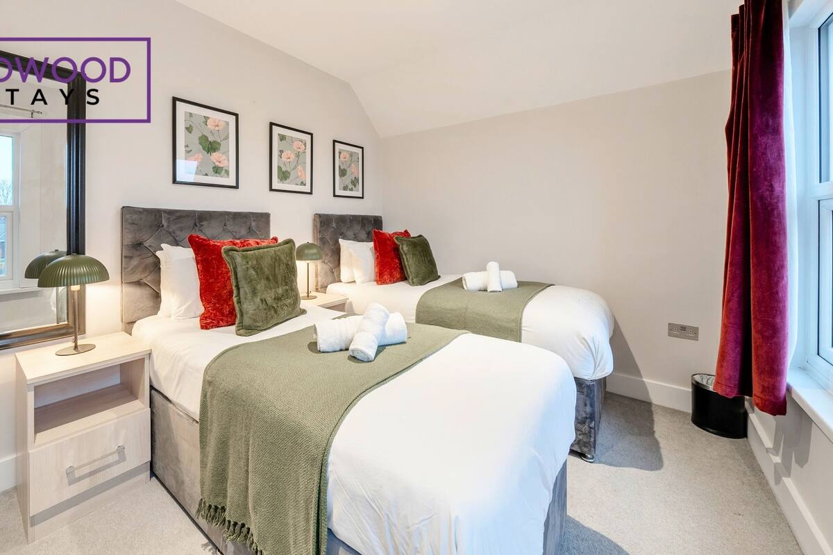 A hotel room with two beds, a nightstand, a mirror, and a window with curtains.