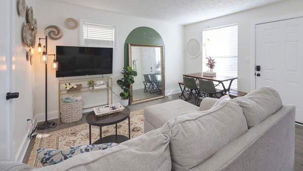 A living room with a sofa, TV, and a dining area with a table and chairs. - Cottage 2 mi to Broadway: King Bed, Fenced Yard (Nashville)