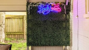 A neon sign with the word "Hometown" in a stylized font, surrounded by greenery and flowers. - Cottage 2 mi to Broadway: King Bed, Fenced Yard (Nashville)