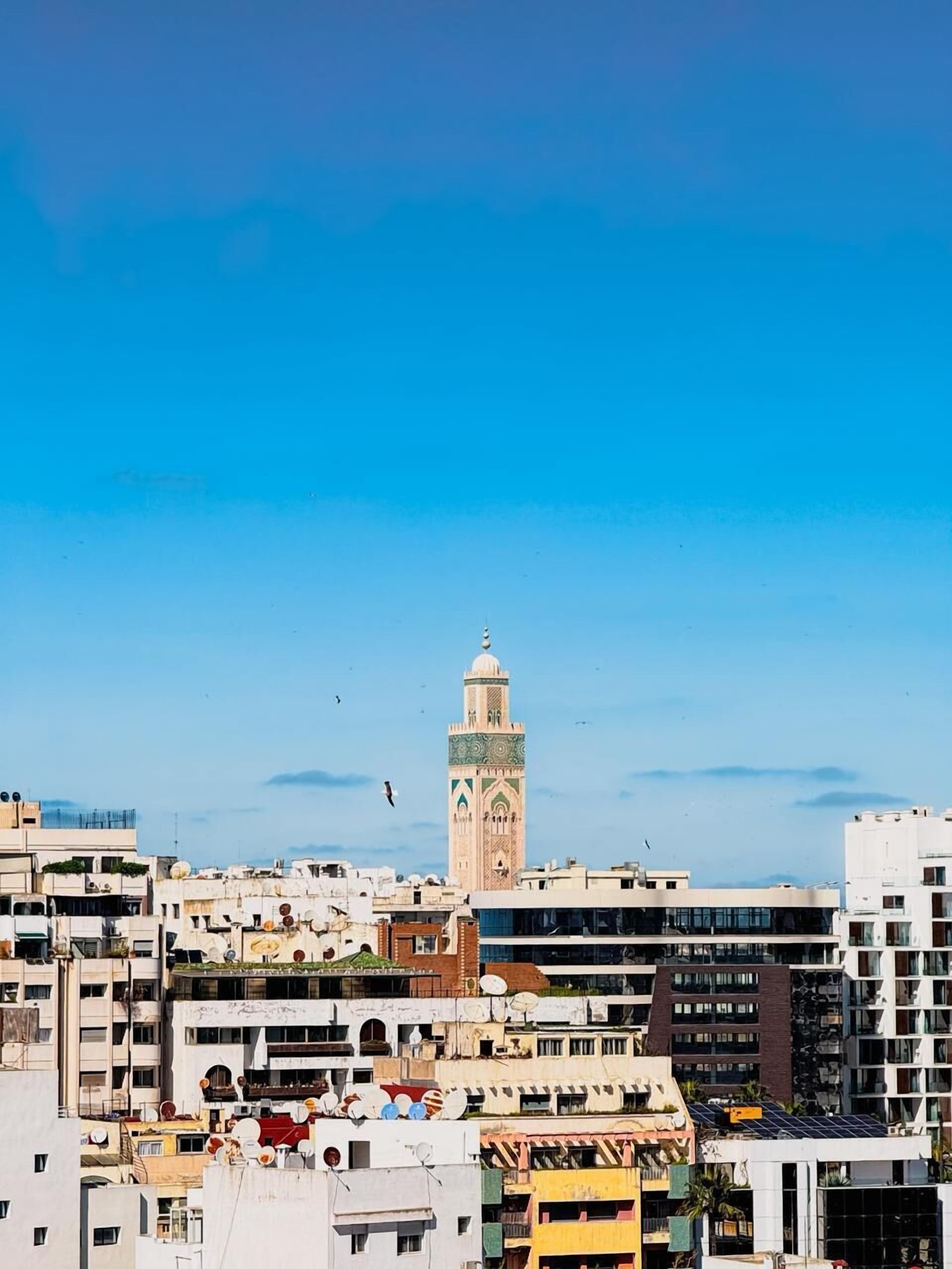 Un paisaje urbano con un alminar destacado, rodeado de edificios de varios pisos y diferentes estilos arquitectónicos.