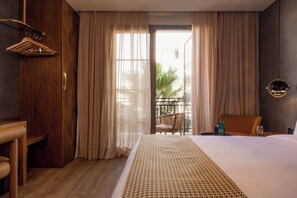 A hotel room with a large bed, wooden furniture, a balcony with a chair, and a view of the outdoors. - Le Square By Onomo Collection (Casablanca)