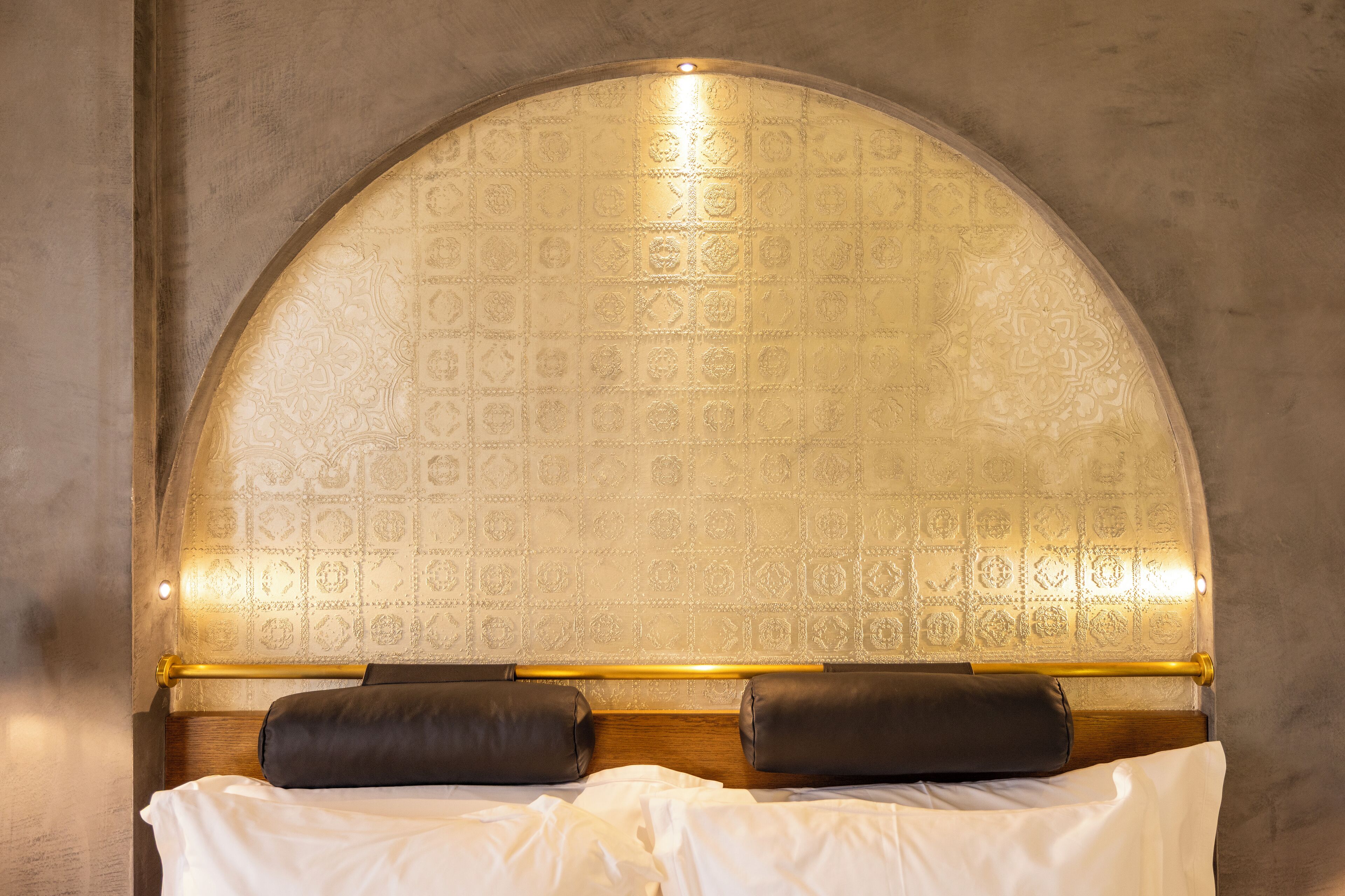 A bed with a headboard, two pillows, and a white bedspread.
